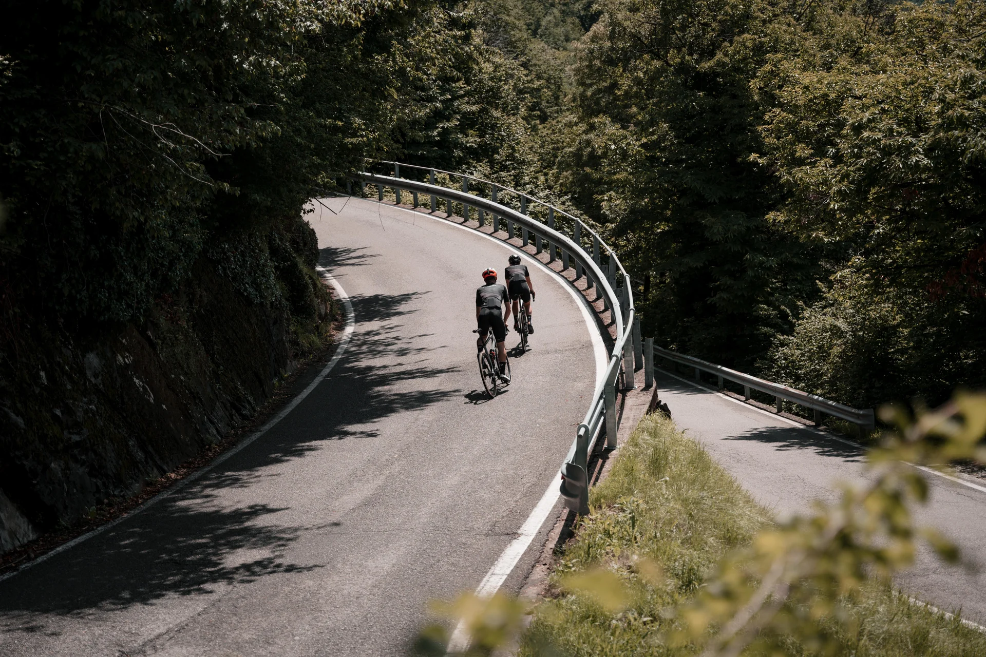 Dois ciclistas numa curva de estrada de montanha